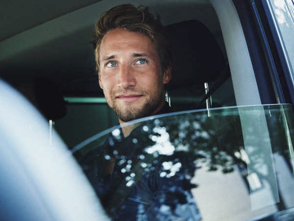 Ung man med nedvevad ruta i förarsätet på en bil