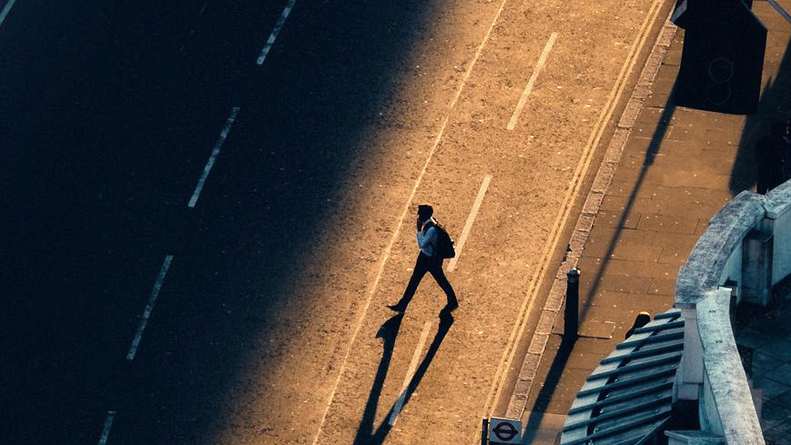 Person går över väg i soluppgång