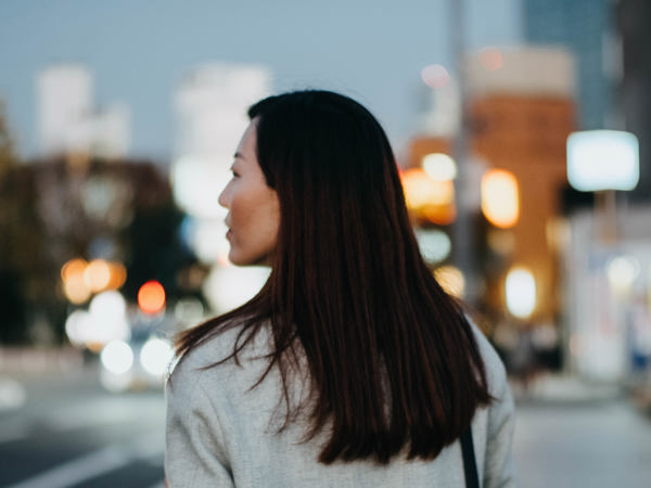 Ryggen på en kvinna som går in en stad.