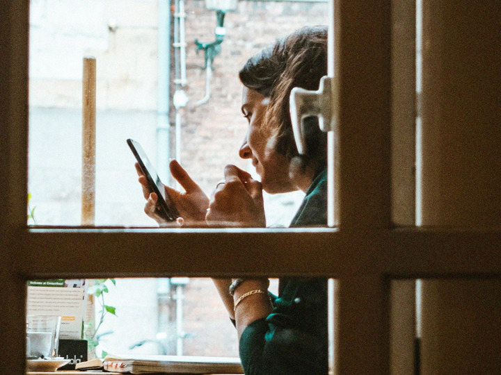 Vy genom fönster, en person som håller i en mobiltelefon.