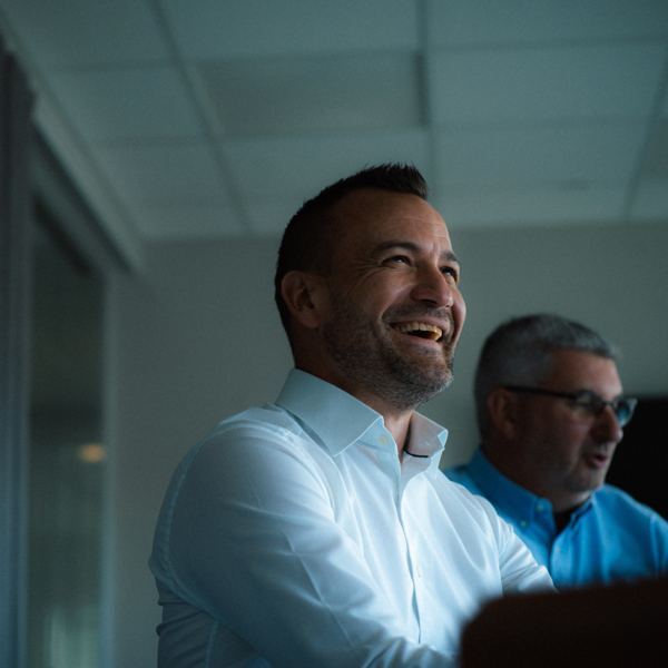 Två män, mannen i förgrunden ler.