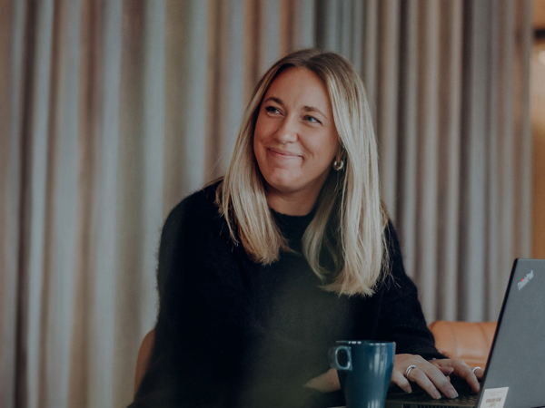 En glad kvinna som använder en laptop.