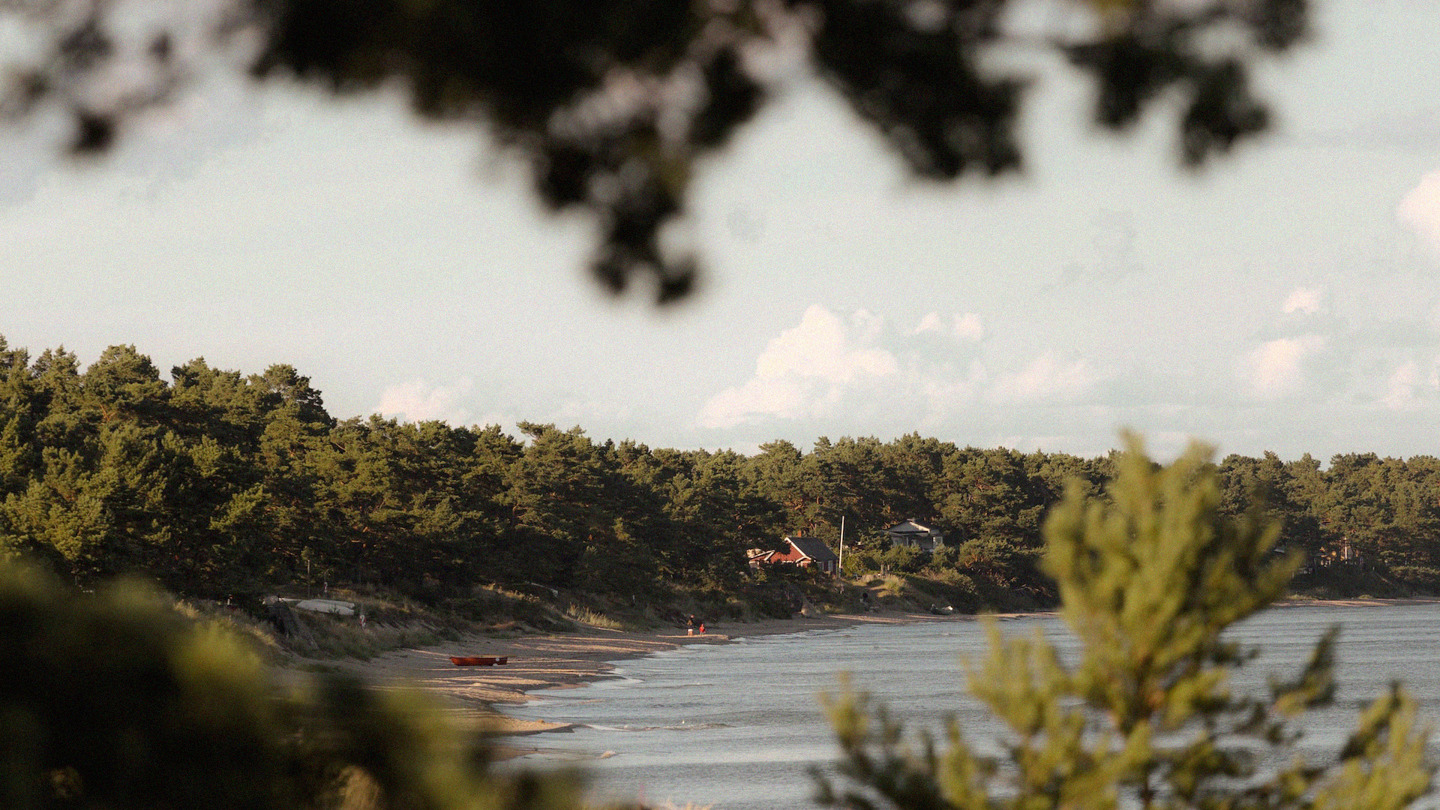A beach in a bay with some houses in the background. Photo.